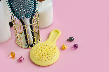 Naklejka na ściany i meble Hair brushes with vitamin capsules on pink background