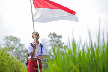 Young Boy In School Uniform Proudly Holding A Large Indonesian Flag