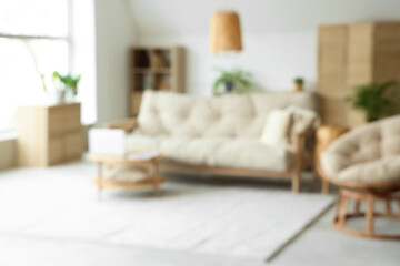 View of blurred living room with sofa, plants and laptop on table