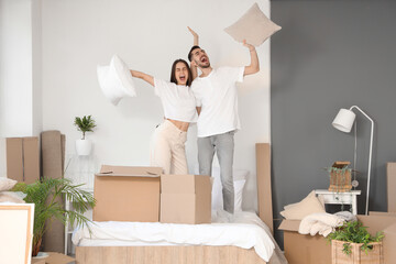 Happy young couple with pillows in bedroom on moving day