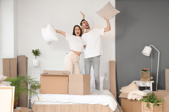 Happy young couple with pillows in bedroom on moving day