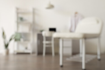 Blurred view of medical office with couch, doctor's workplace and shelf unit