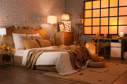 Interior of stylish bedroom with autumn decorations and candles in evening