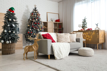 Interior of living room decorated for Christmas with sofa, shelving unit and dresser near white...
