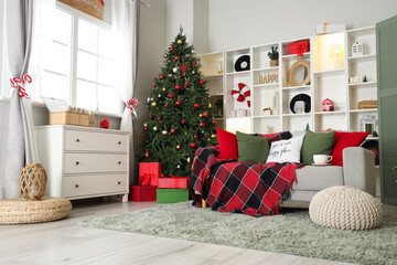 Interior of living room decorated for Christmas with sofa, shelving unit and dresser near window