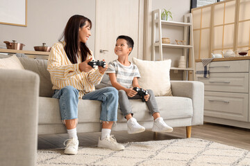 Young mother and her little son playing video games at home © Pixel-Shot
