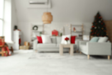 Blurred view of light living room with sofa and Christmas plant poinsettia on table
