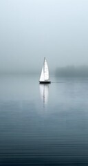 Obraz premium Solitary Sailboat Journey Across Misty Waterscape Stillness