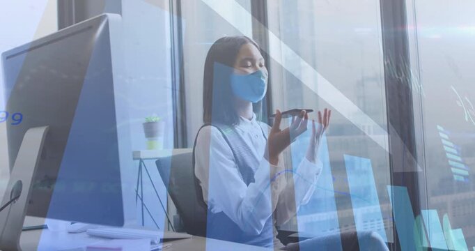 Executive lifting smartphone in office, talking and referencing data charts sweeping over window