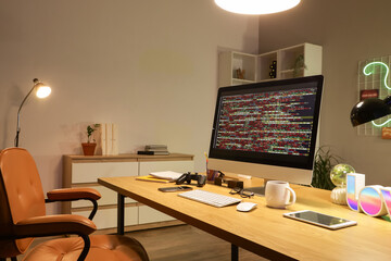 Programmer's desk with computer and glowing lamps in office at night