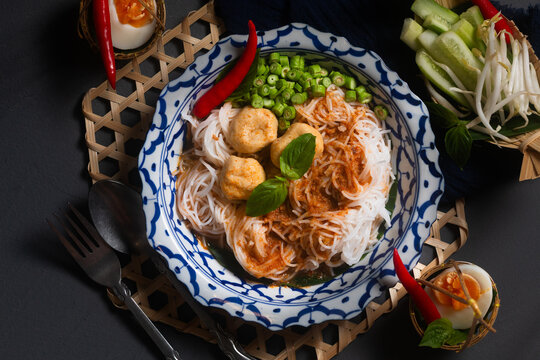 Food concept Thai authentic kanom jeen Nam Ya fermented rice noodles served with a fish flavorful curries fresh and vegetables on black background with copy space