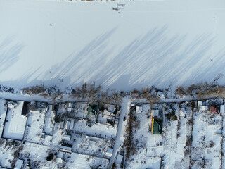 Aerial view of snow-covered houses near frozen river in Uralsk, Kazakhstan, during winter. c.