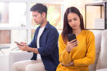 Unhappy asian couple sitting on sofa having relationship problem in living room at home, emotion...