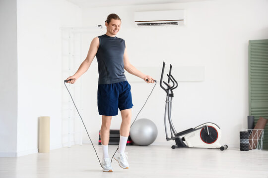 Sporty young man jumping with rope at gym - Powered by Adobe