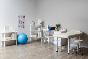Interior of physiotherapist's office with workplace, couch and shelf units