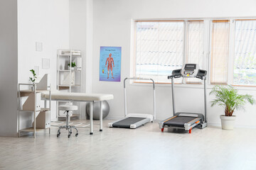 Interior of physiotherapist's office with couch, treadmills and shelf units