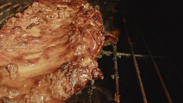 Close up of flames underneath a slab of spareribs being grilled on a barbecue