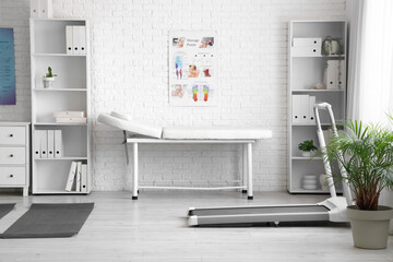 Interior of physiotherapist's office with couch, treadmill and shelf units