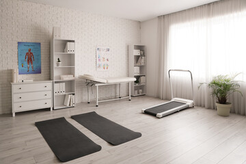 Interior of physiotherapist's office with couch, fitness mats and treadmill