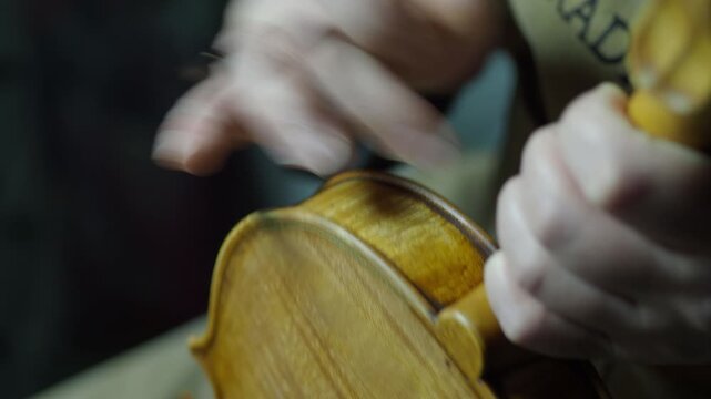 Luthier applying varnish with precision on a newly crafted violin, using an antiquing technique to give the instrument an aged appearance, all within the serene atmosphere of the workshop