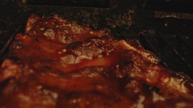 Beautiful macro dolly in of grilled ribs on a barbecue. The meat is juicy and nicely cooked