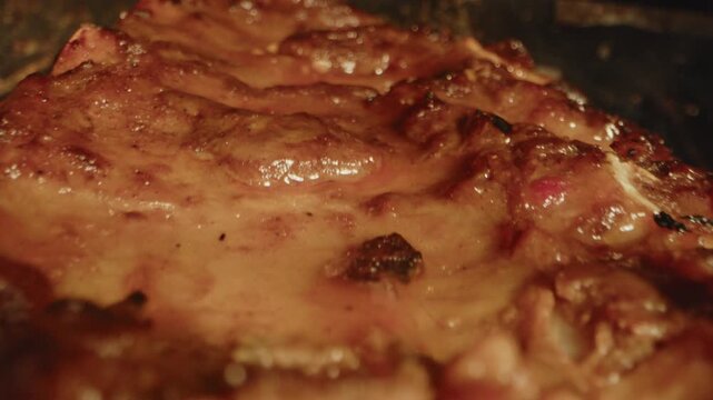 Extreme close up of a rack of spareribs being grilled on a barbecue grate with smoke coming from the meat