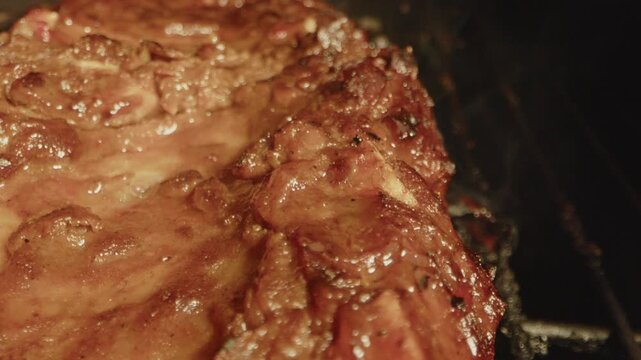 Beautiful macro of spareribs slowly being grilled on a barbecue with smoke rising from the meat