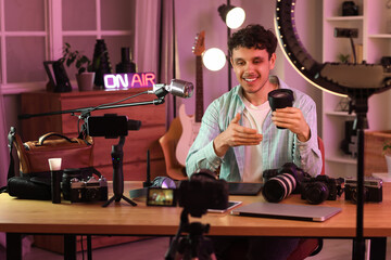 Male blogger with camera lens recording video at home