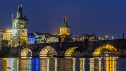 Naklejka premium The Charles Bridge day to night timelapse over the Vltava River reflected in water in Prague, Czech Republic