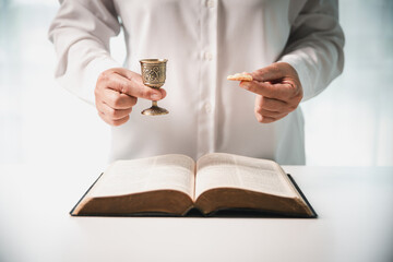 During the holy communion ceremony in church, a hand is extended in faith to receive the sacred...
