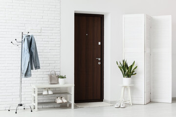 Interior of hallway with door, shoe stand and clothes rack