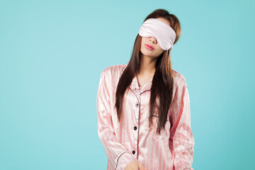Asian woman in pajamas, portrait with eye mask cover for sleep, young beauty follows her routine to...