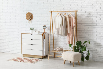 Interior of hallway with clothes rack, pouf and commode