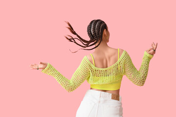 Young woman in crochet top with dreadlocks on pink background, back view