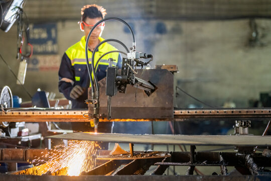 CNC Machine Operation: Male Engineer in Gloves and Safety Glass Cutting Metal with Sparks Technician Cutting Steel with CNC Machine in a Messy Old Factory Worker Using CNC for Steel with Heat