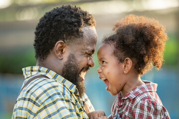 Happy african black parents dad father with daughter child on piggyback teasing fun in garden...