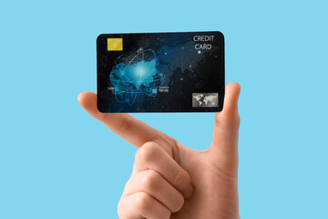 Female hand with credit card on blue background, closeup