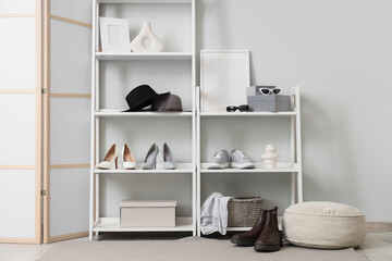 Interior of light hallway with shelf units, women's shoes and folding screen