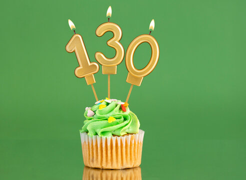 Number 130 birthday candle - Cupcake on a green background