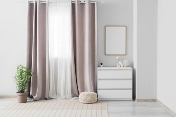 Interior of light room with grey curtains, commode and frame