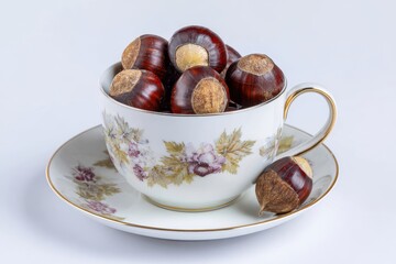 Horse chestnut nuts in a cup against a white background
