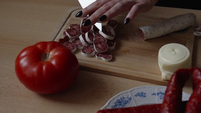 Fuet salami being sliced in the kitchen, woman preparing food, rustic atmosphere, close-up.
