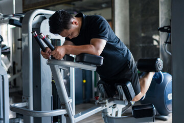 Focused Asian man engages in intense workout routine at modern gym during afternoon, strengthening...