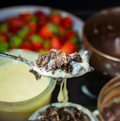 sweet on a spoon with cookies and white cream with strawberries