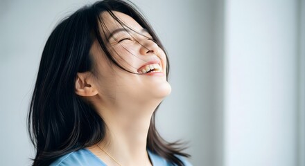 Fototapeta premium Joyful Young Asian Woman Laughing with Eyes Closed
