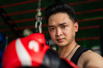 Young athlete demonstrating focus while holding boxing gloves in a training environment at a gym...