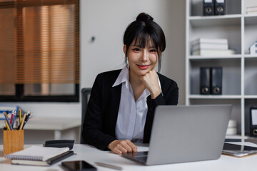 Fototapeta premium An attractive young Asian woman sitting at a laptop in a workplace office. 