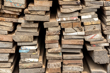 Pile of weathered wooden planks, stacked high and ready for use in construction or carpentry....