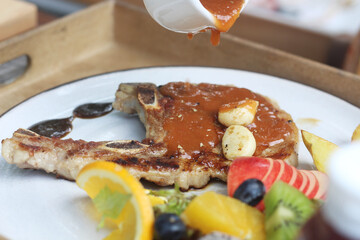 A delicious grilled pork chop served with garlic, brown sauce, and sides of potato