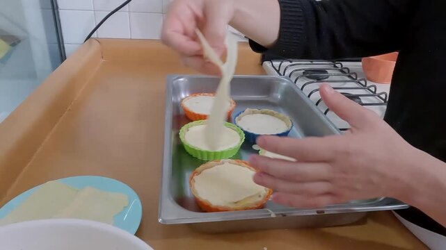 Pastry professional crafting quiche, positioning dough inside vibrant silicone molds during culinary preparation within contemporary kitchen setting